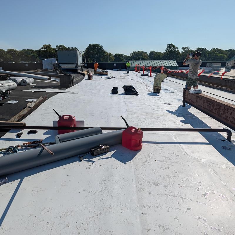 TPO single-ply roof with restoration tools and workers