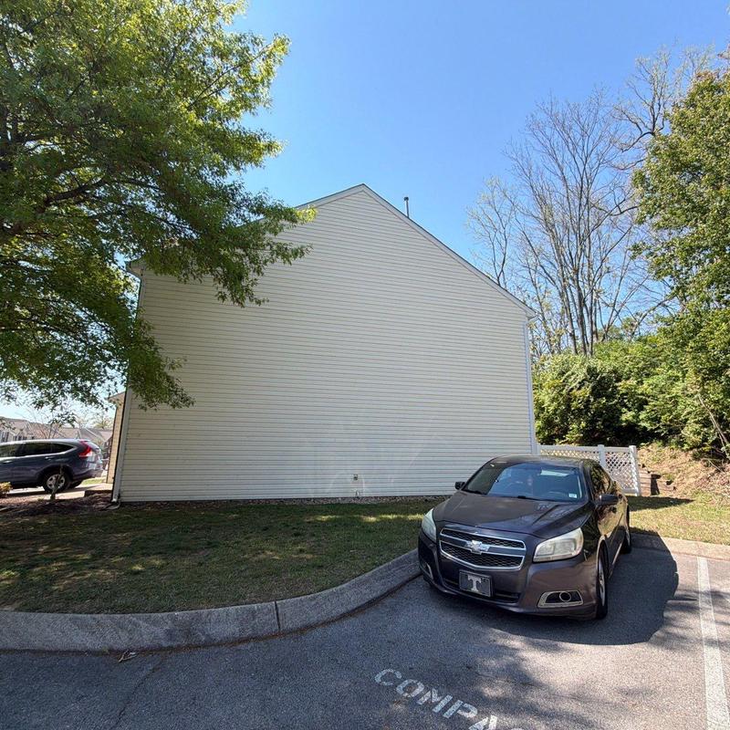 Vinyl siding exterior wall and parked car near curb