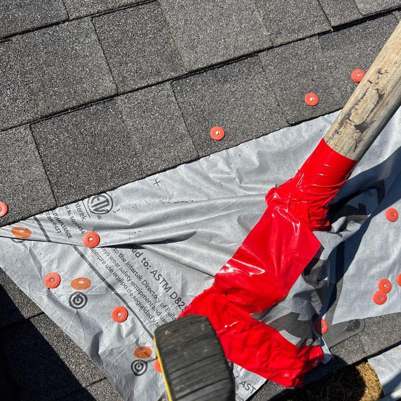 Roofing underlayment with red plastic caps and tool handle