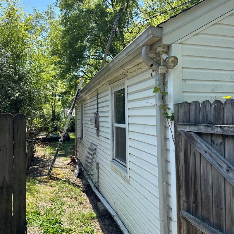 Vinyl siding inspection with ladder in backyard
