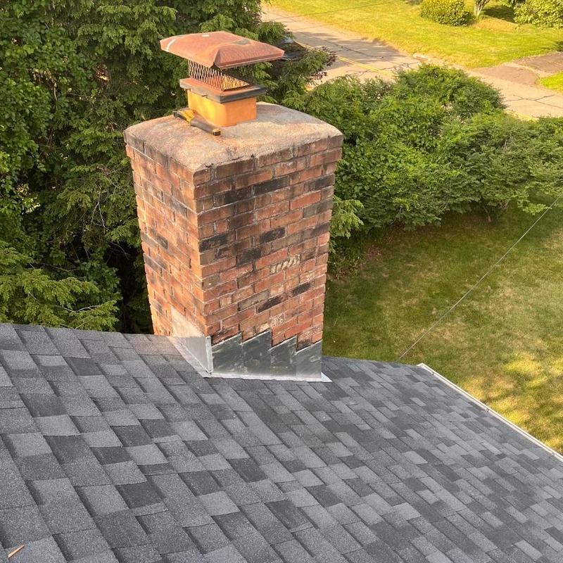 Brick chimney with metal flashing on new shingle roof