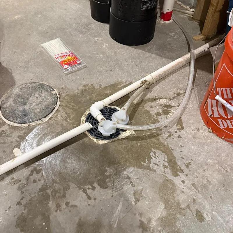 Floor drain with PVC piping and hose in basement
