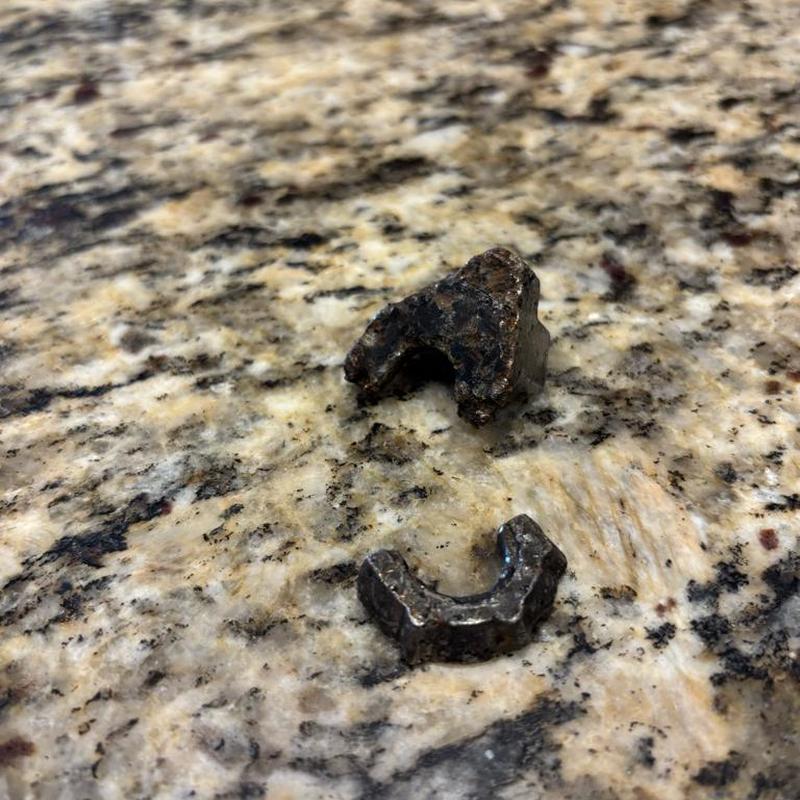 Broken garbage disposal metal parts on granite countertop