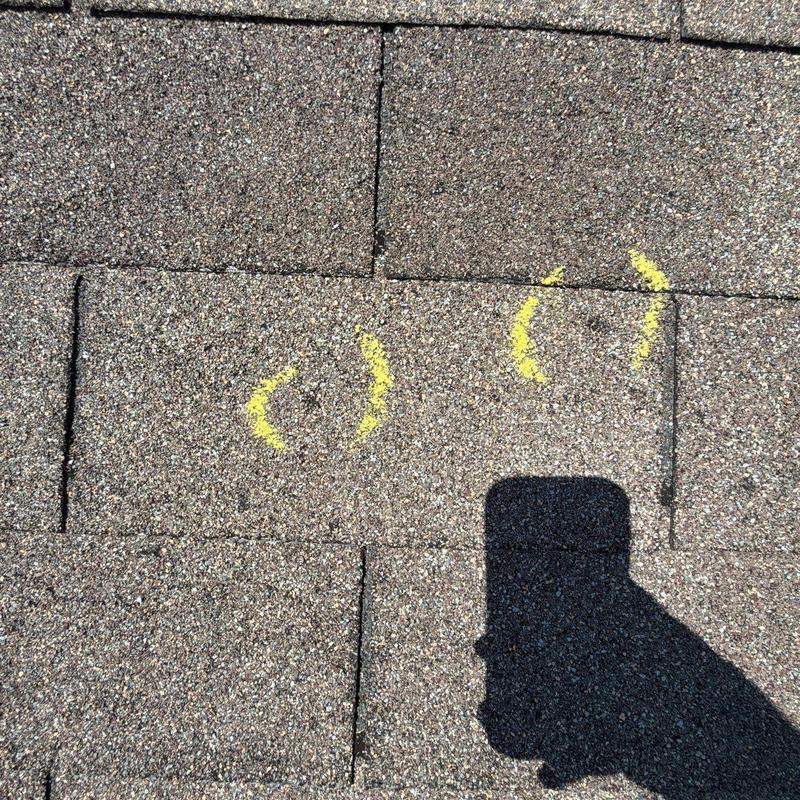Roofing shingles with marked hail damage spots