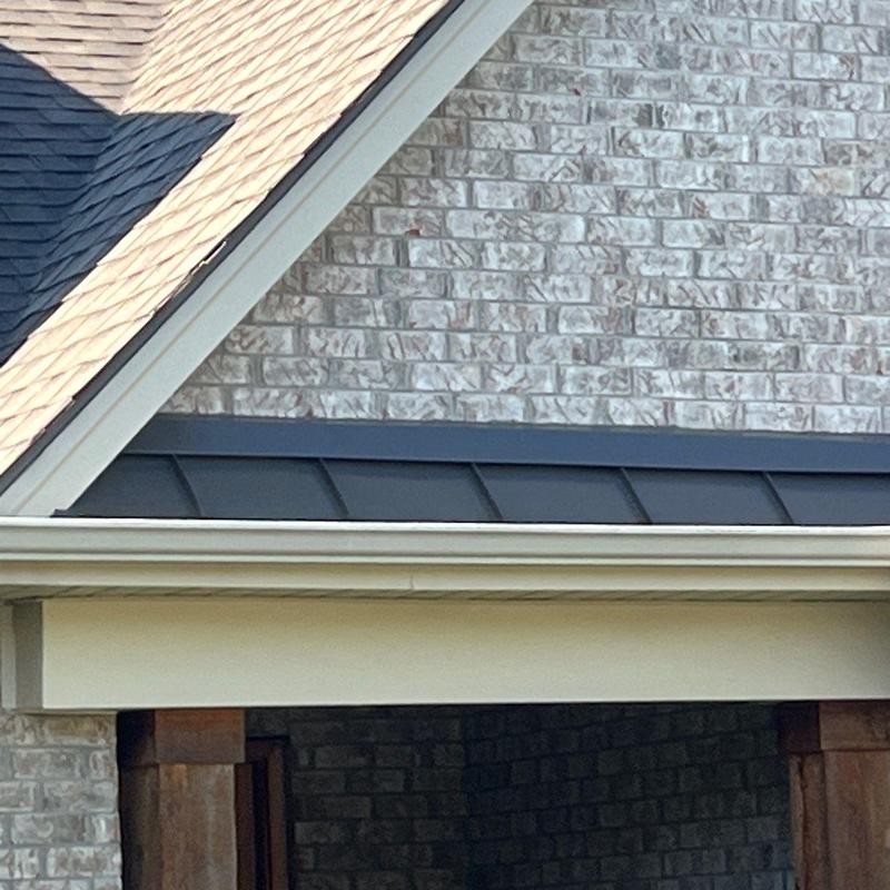 Metal roof edging on brick house under shingle roof