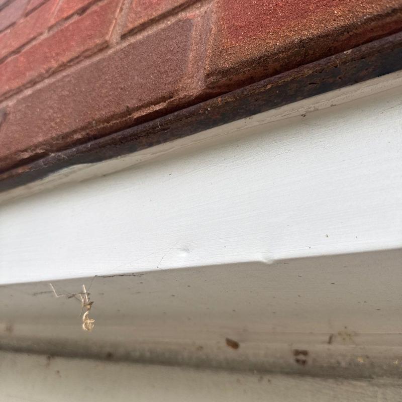Metal flashing under brick wall with rust spots
