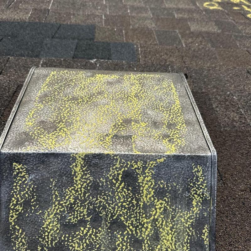 Roof shingles with hail damage markings on vent cover