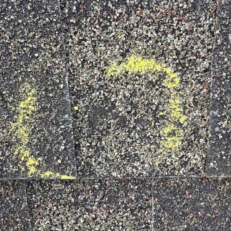 Asphalt shingle with yellow chalk hail damage marks