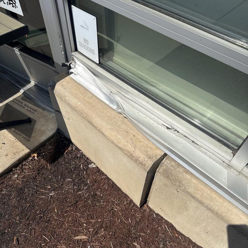 Window frame with dent and exterior damage near door