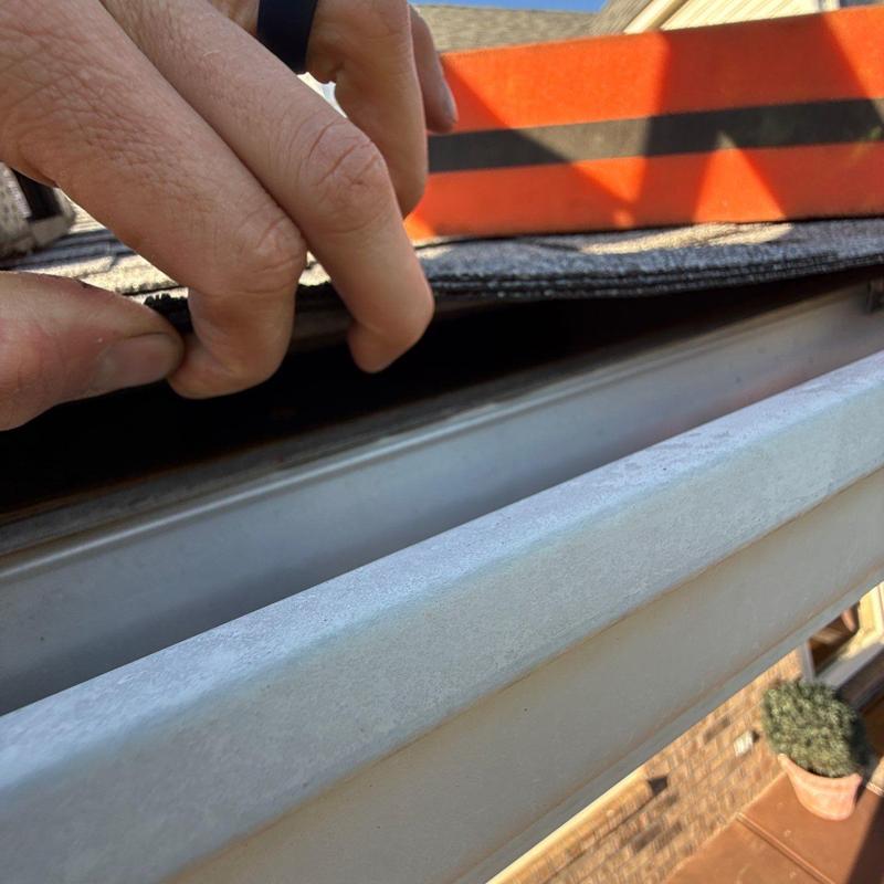 Roof shingles lifted to inspect gutter edge