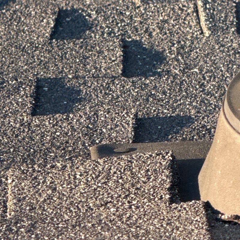 Roof shingles with hail impact damage near vent pipe