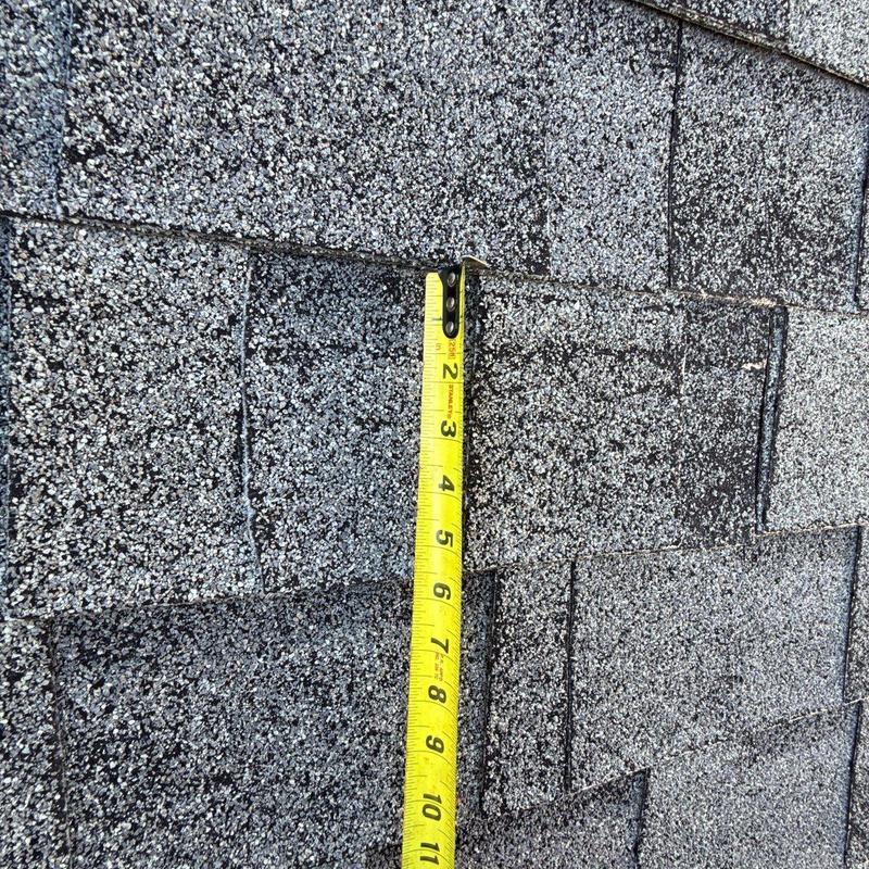 Roof shingles with measuring tape for damage assessment