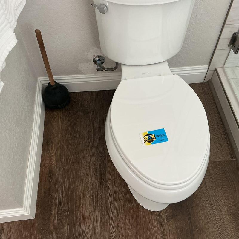 Toilet installation with plunger on hardwood floor Toilet installation with plunger on hardwood floor