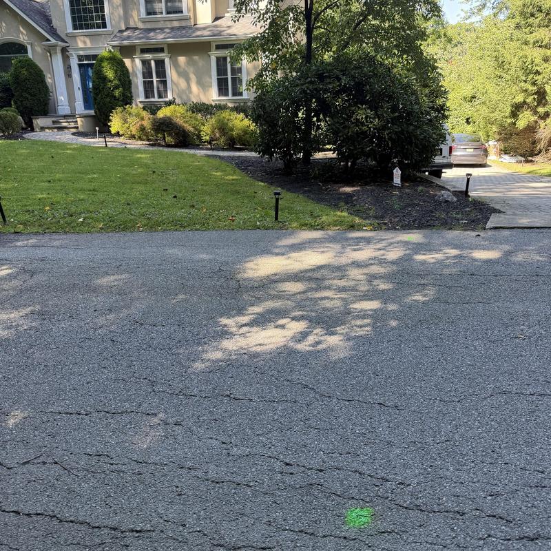 Sewer line location markings on cracked asphalt driveway Sewer line location markings on cracked asphalt driveway