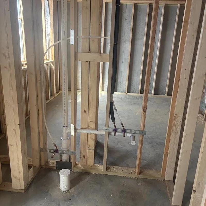 Plumbing rough-in with PVC pipes in wooden framing