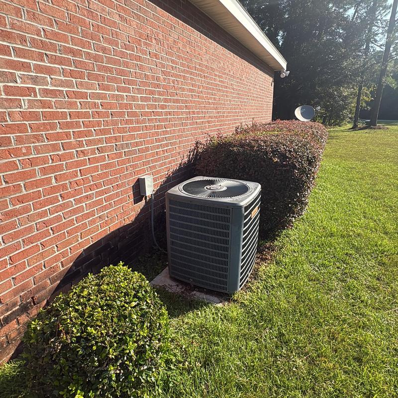 Outdoor air conditioner unit beside brick house and bushes Outdoor air conditioner unit beside brick house and bushes