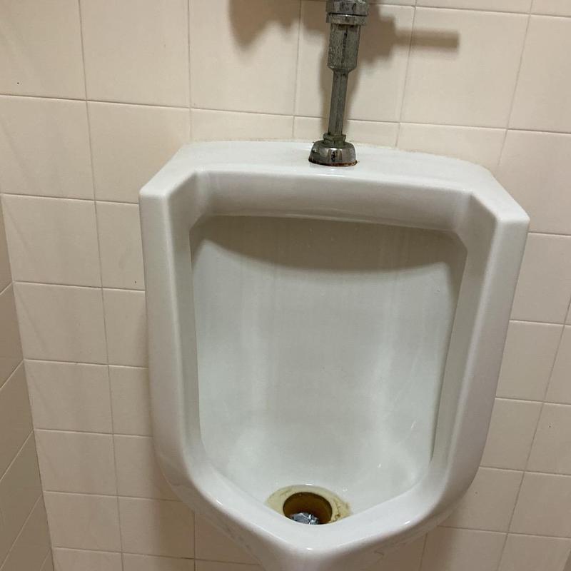 Commercial urinal with flush valve plumbing repair Commercial urinal with flush valve plumbing repair