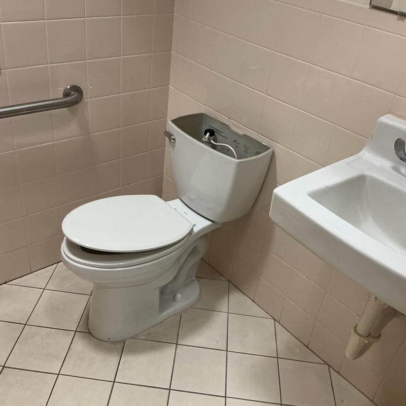 Commercial toilet with open tank lid in restroom Commercial toilet with open tank lid in restroom