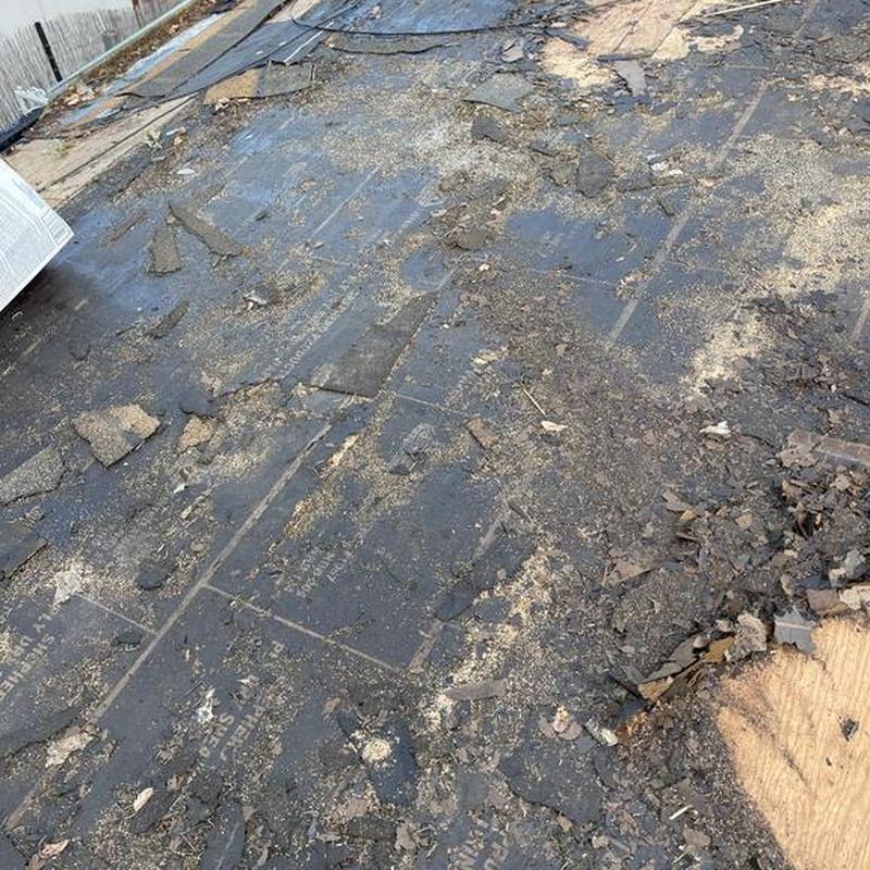 Asphalt roof tear-off with debris on plywood deck