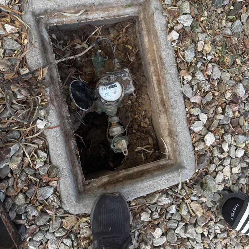 Water meter box exposed for leak inspection in yard Water meter box exposed for leak inspection in yard