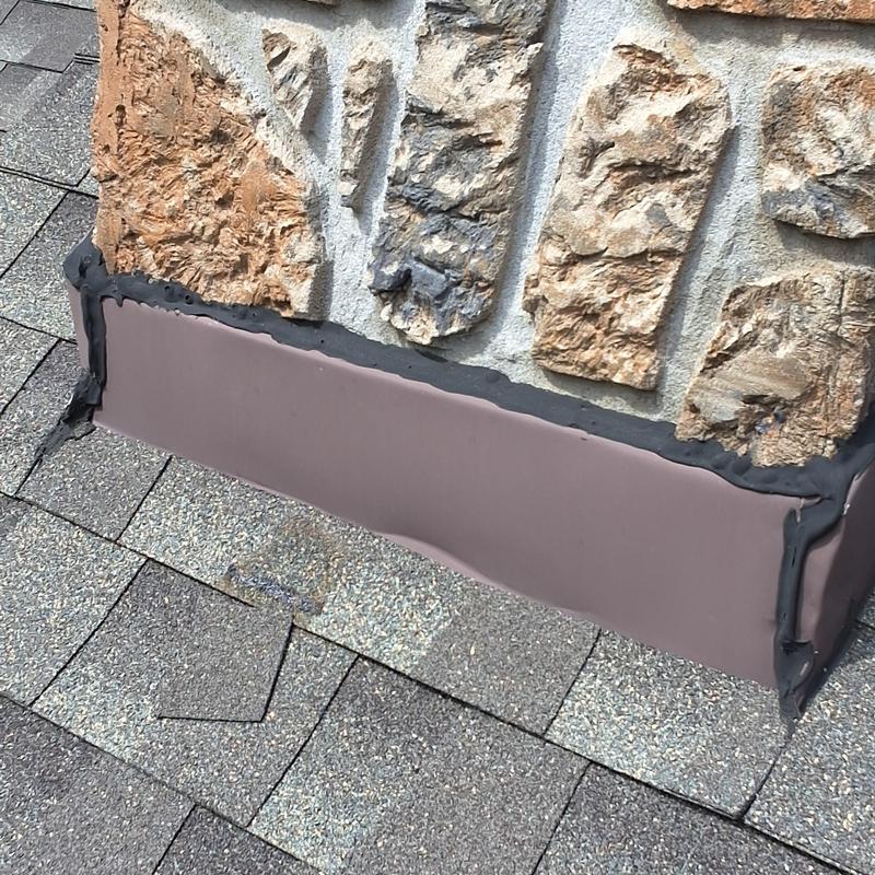 Chimney base flashing with sealant on shingle roof Chimney base flashing with sealant on shingle roof