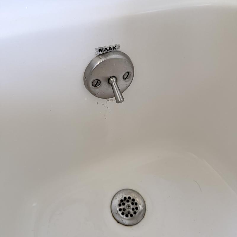 Shower valve handle and bathtub drain in white tub Shower valve handle and bathtub drain in white tub