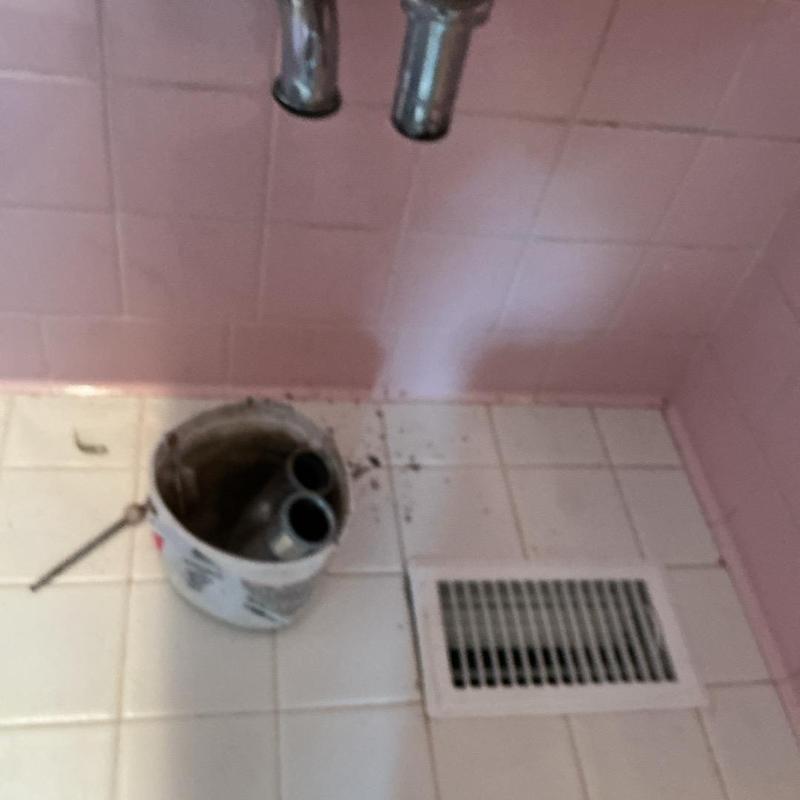 Sink drain pipes removed for repair under pink tile wall Sink drain pipes removed for repair under pink tile wall