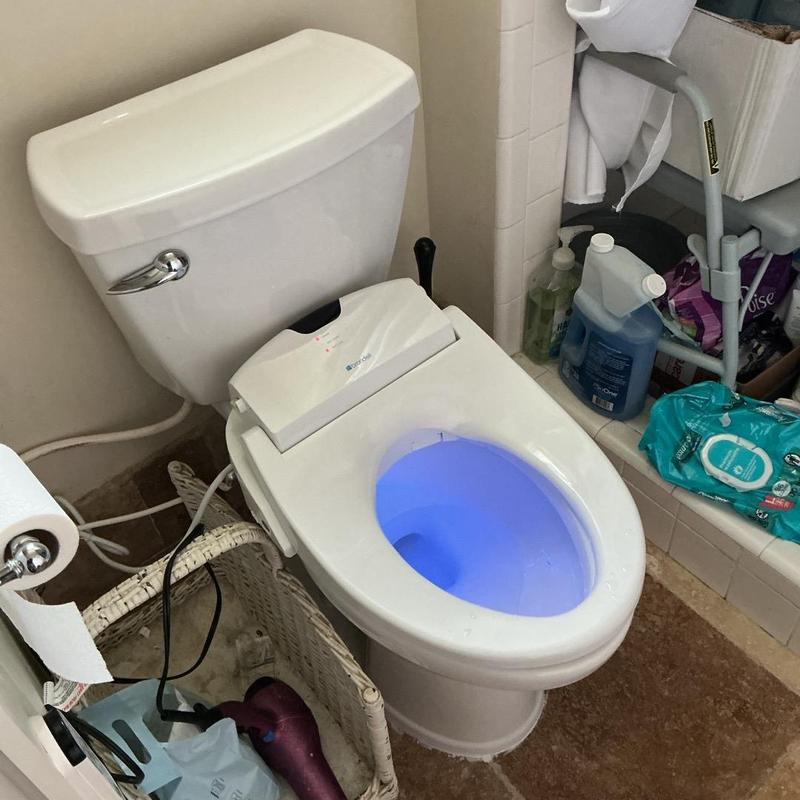 Bidet toilet seat installation with blue light on toilet bowl Bidet toilet seat installation with blue light on toilet bowl