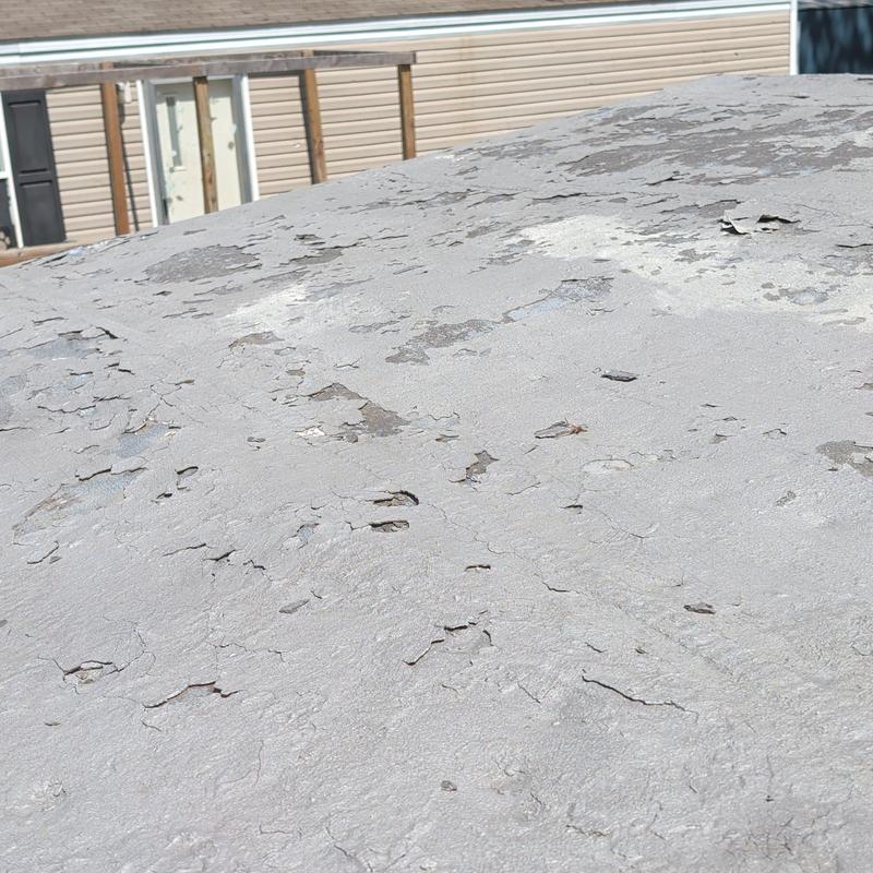 Metal mobile home roof with hail damage and peeling coating
