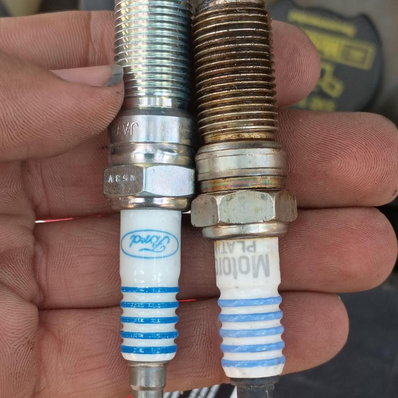 Spark plugs comparison: new vs old in hand close-up Spark plugs comparison: new vs old in hand close-up
