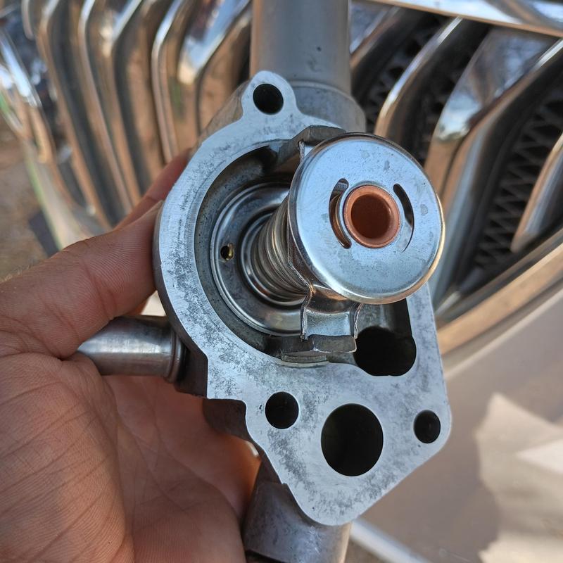 Thermostat assembly held by hand near vehicle grille Thermostat assembly held by hand near vehicle grille