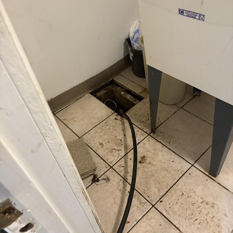 Floor drain jet cleaning with hose in tiled room Floor drain jet cleaning with hose in tiled room