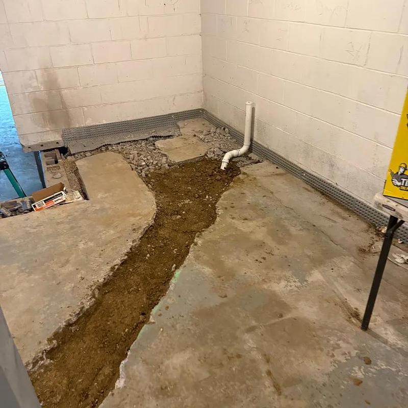 Basement plumbing trench with exposed pipe in concrete floor