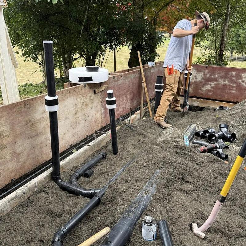 ABS drain piping rough-in with worker leveling sand ABS drain piping rough-in with worker leveling sand