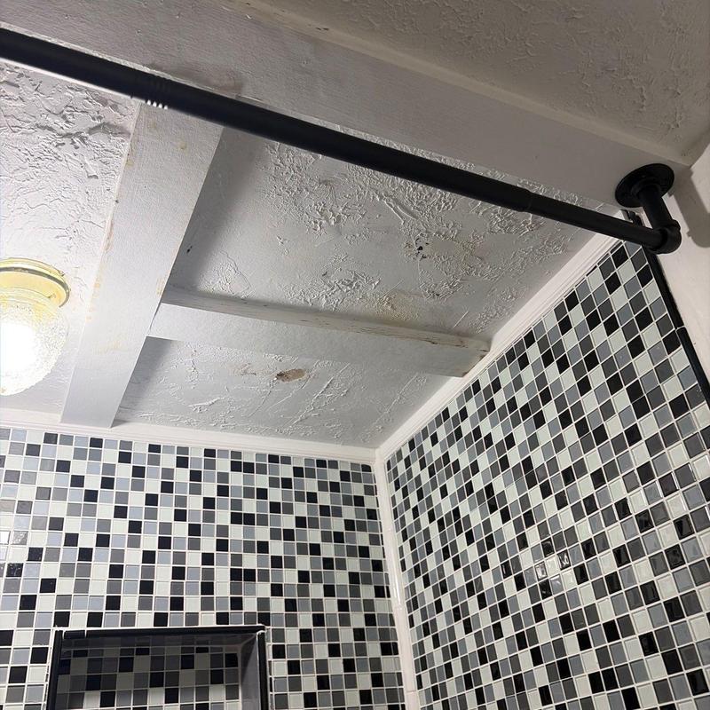 Bathroom ceiling with water stains and black shower rod