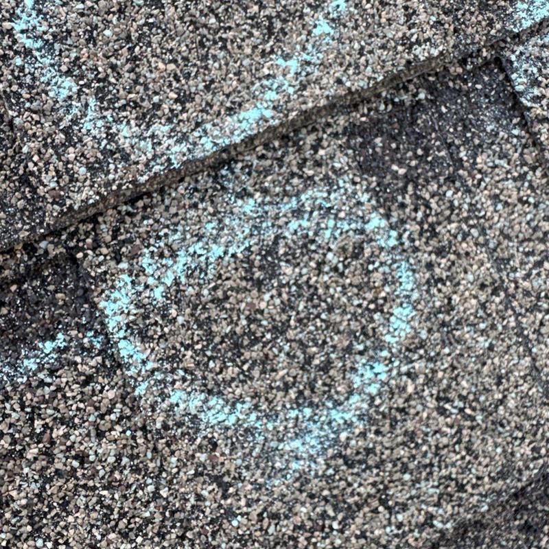 Roof shingles with hail damage marked in blue chalk