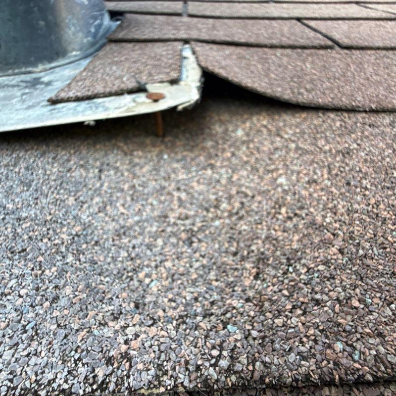 Roof shingles with lifted flashing and nail exposed