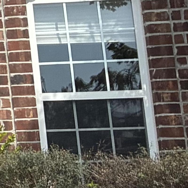 Hail-damaged front window on brick house exterior