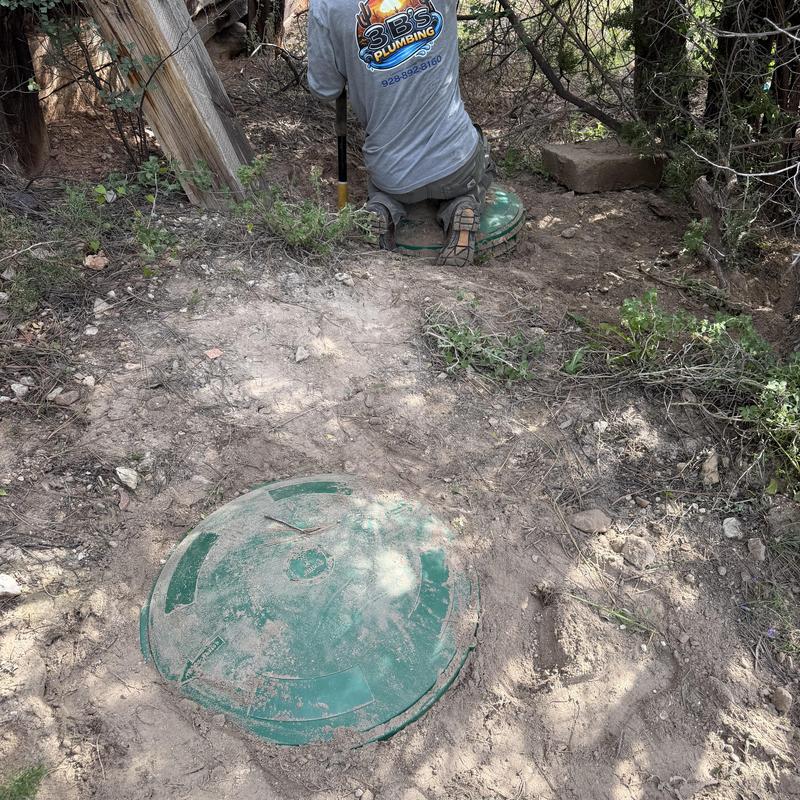 Septic tank with green risers and technician digging nearby Septic tank with green risers and technician digging nearby