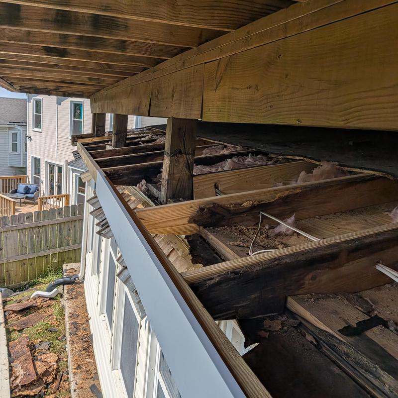 Deck wood framing with rot damage and exposed insulation Deck wood framing with rot damage and exposed insulation