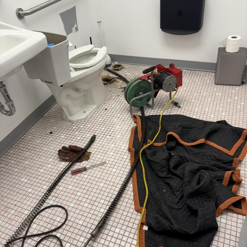 Toilet sewer drain auger machine setup in restroom Toilet sewer drain auger machine setup in restroom