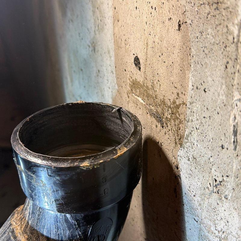 Main stack waste pipe opening near concrete wall