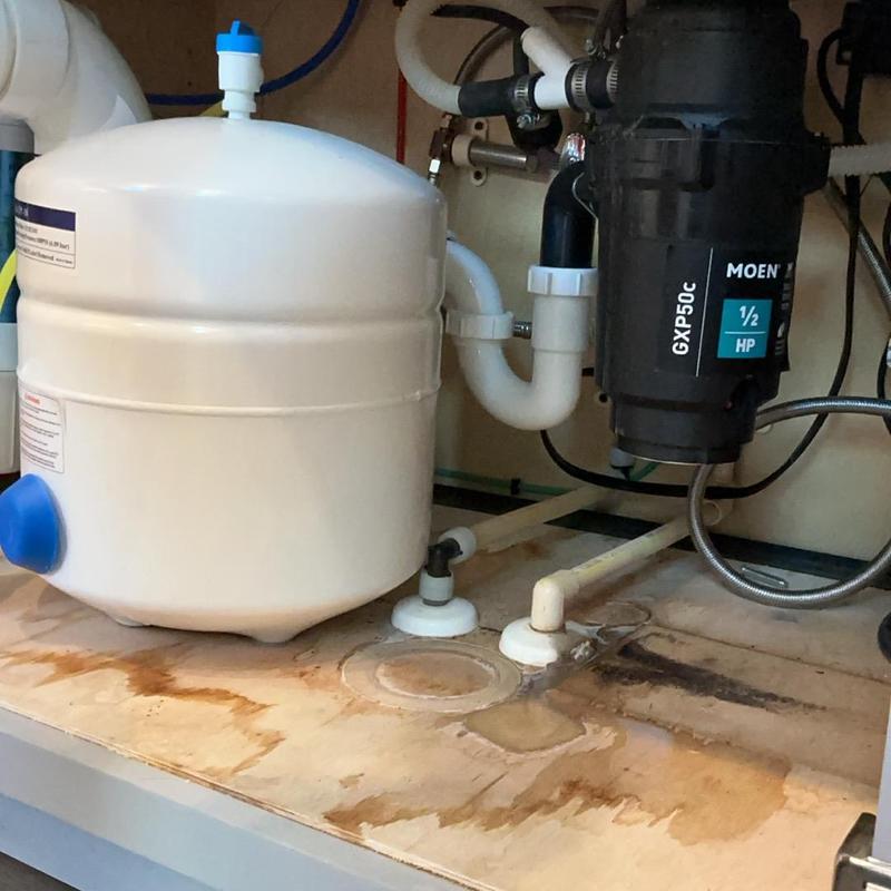Garbage disposal and water tank under kitchen sink with leak stains Garbage disposal and water tank under kitchen sink with leak stains