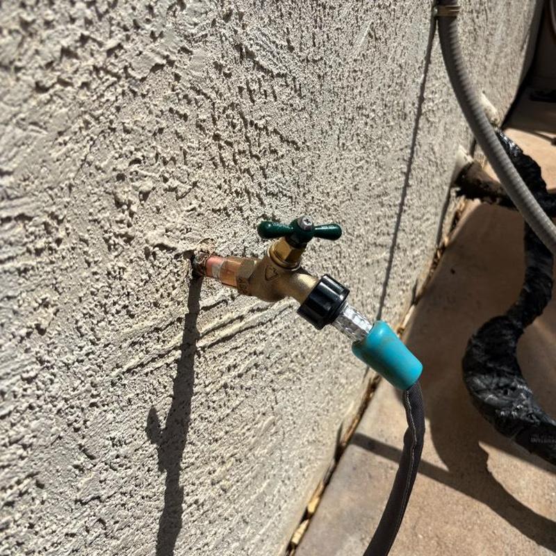 Hose bib with attached garden hose on exterior wall
