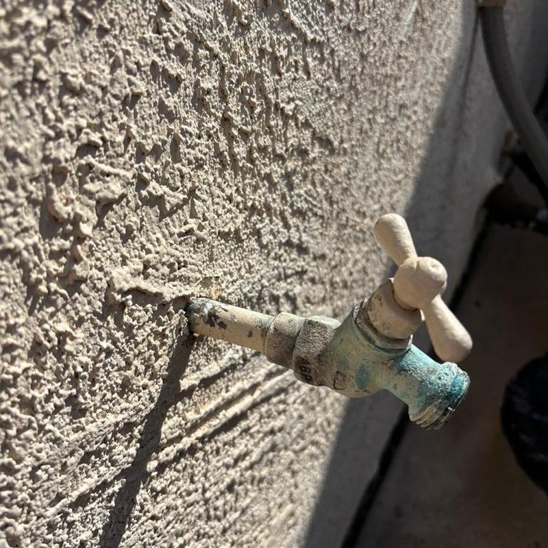 Outdoor hose bib with corrosion on stucco wall