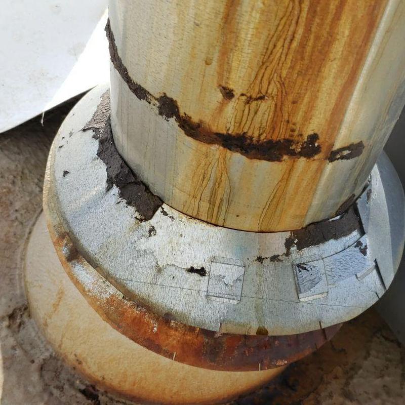 Metal pipe jack with rust and sealant damage on flat roof