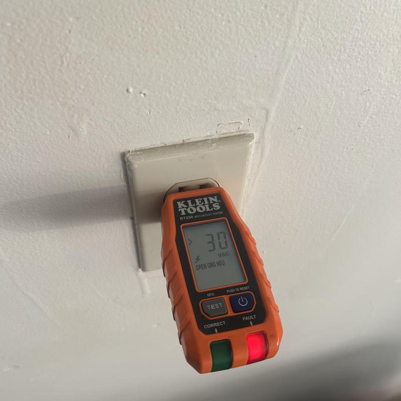 Electrical outlet voltage tester on wall outlet