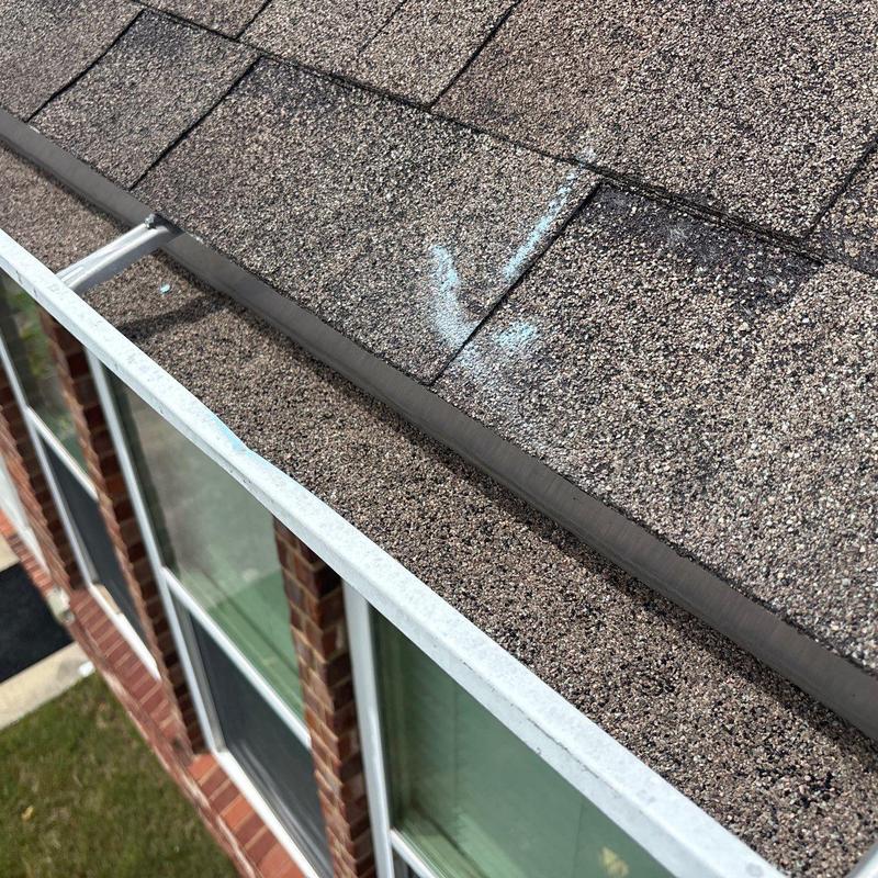 Asphalt shingles with hail damage markings on roof edge