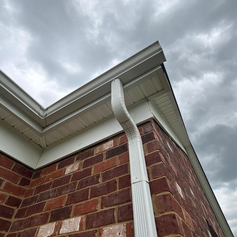 Gutter downspout and roof edge inspection under cloudy sky
