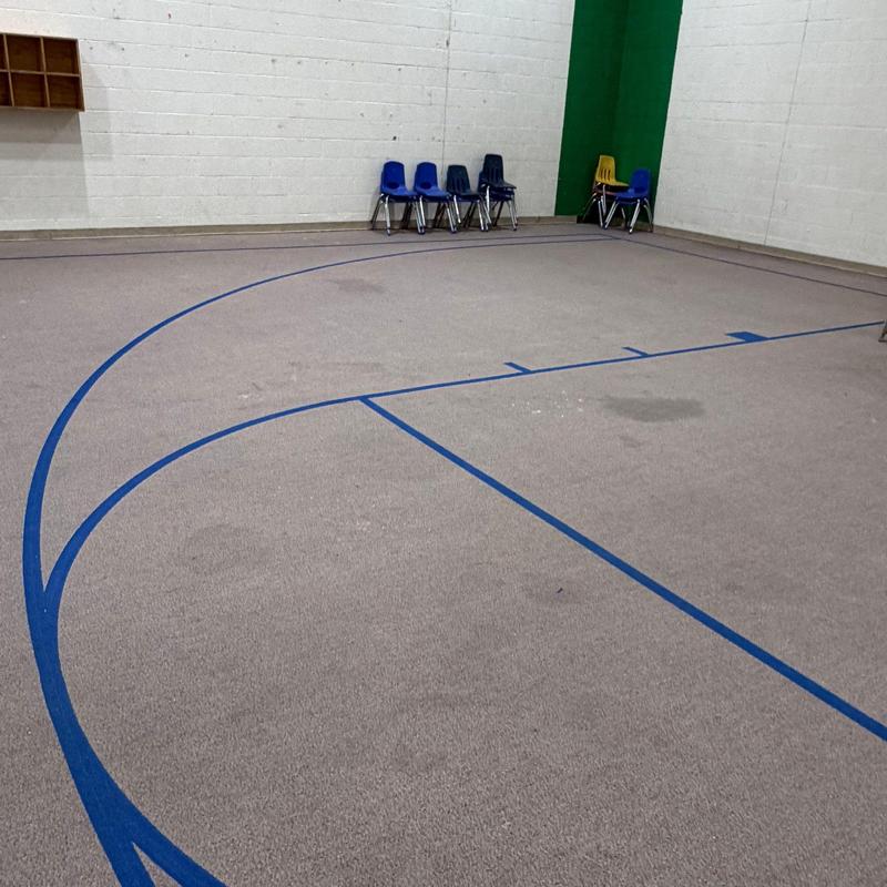 Indoor gymnasium carpet with blue court lines and chairs